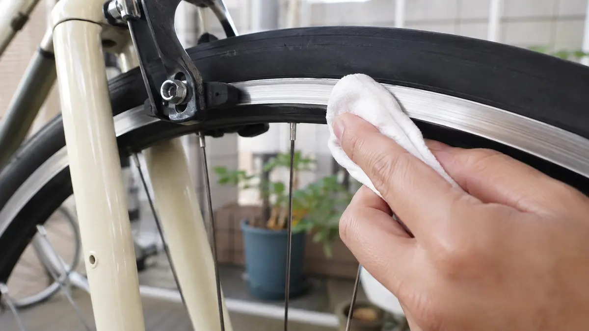 自転車のリムを布で清掃してブレーキの音鳴りを対策する様子