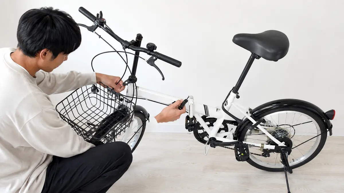 20インチ折りたたみ自転車の組み立てとヒンジ確認 20インチ折りたたみ自転車の中央ヒンジを確認しながら組み立てる日本人男性