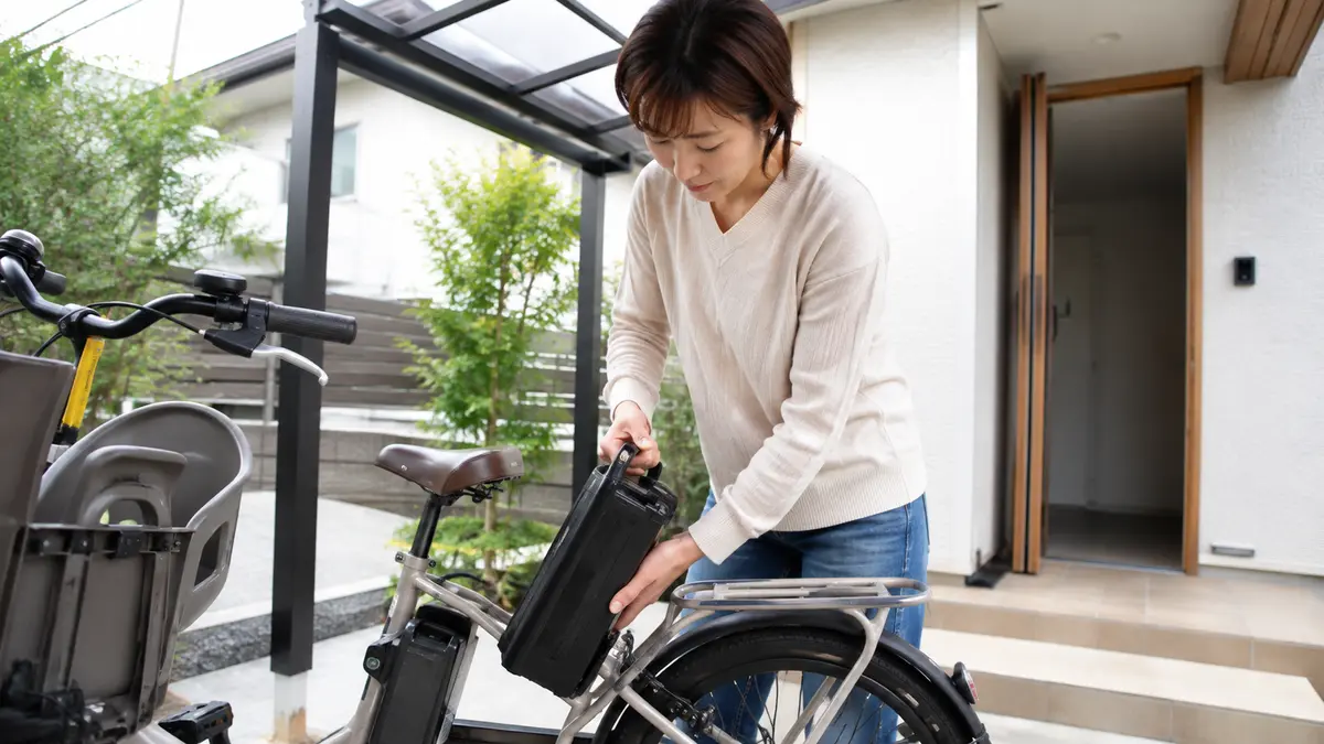 日本人女性が電動自転車からバッテリーを外して室内に持ち込む様子